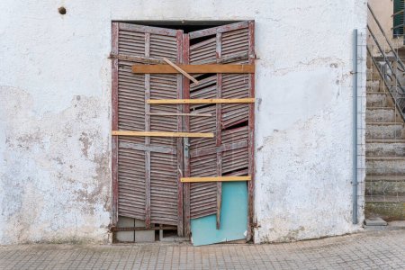 Geschlossener Eingang mit mallorquinischen Fensterläden eines alten Gebäudes in einem fortgeschrittenen Zustand des Verfalls und der Verlassenheit. Insel Mallorca, Spanien