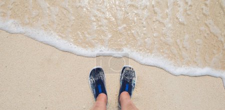 Weibliche Füße mit Wasserschuhen am Strand. Strand- und Wassersportkonzept: Schwimmschuhe in Neopren zum Kajakfahren, Paddeln, Schnorcheln. Blick von oben.