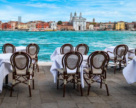 Téléchargez les photos : Tables et chaises en plein air un restaurant avec vue sur le canal à Venise, Italie. - en image libre de droit