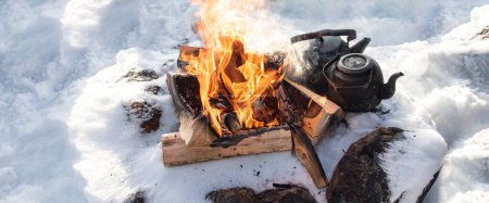 Téléchargez les photos : Feu de camp d'hiver dans la neige. Réchauffer avec une théière près du feu. - en image libre de droit