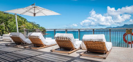 Relax y concepto de vacaciones de verano: tumbonas de lujo en la piscina en destino tropical.