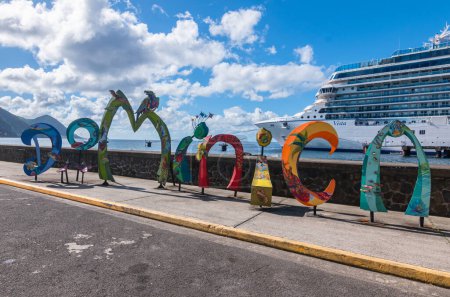 Téléchargez les photos : Roseau, Dominique - 24 novembre 2023 : Panneau à mots dominicain devant Oceania Cruises Vista navire dans le port de croisière de Roseau. - en image libre de droit
