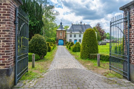 Pfarrhaus der Pfarrei Sint-Martinus mit Eisentor, gepflasterter Auffahrt und schönem Garten, Wezemaal, Hageland, Belgien.