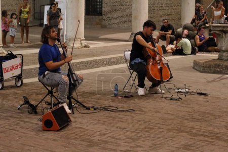 Photo for Ferrara, Italia - August 26, 2022: The Ferrara Buskers Festival is dedicated to the art of the street. VersaDuo, playing a combination of classical and popular styles, which frame the repertoire in a classic POP language. - Royalty Free Image