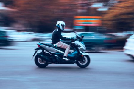 Photo for Motorcyclist on a 125cc scooter speeding through the city. Motorbike riding in the city as a concept of speed. Motion image. - Royalty Free Image