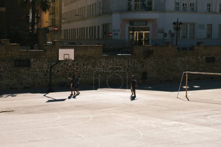 Foto de Cádiz, Andalucía, España; 25 de noviembre de 2023: Amigos jugando baloncesto en un día soleado. Amigos jugando baloncesto en una cancha urbana. - Imagen libre de derechos