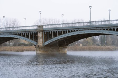 Enrique-Estevan-Brücke, auch als Neue Brücke bekannt, über den Fluss Tormes in Salamanca (Kastilien und Len). Metallbrücke, die von Granitpfeilern gestützt wird. Brücke an einem kalten Wintertag fotografiert.