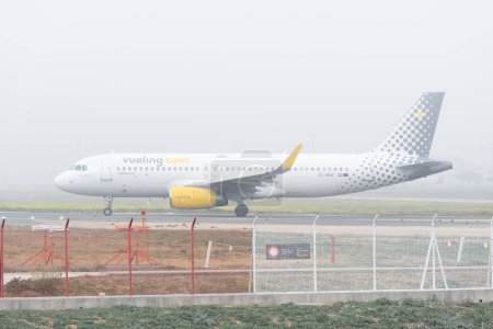 Téléchargez les photos : Séville, Espagne ; 6 février 2024 : Avion de passagers Airbus A320 de la compagnie aérienne Vueling sur la piste de l'aéroport par une journée brumeuse. - en image libre de droit