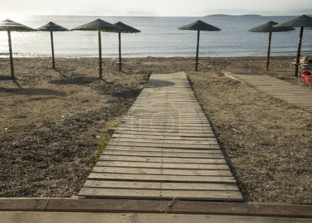 wooden walkway and umbrellas on the summer beachat morning