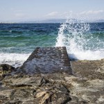 Mediterranean landscape - sea wave hitting a stone pier. Greece, island Aegina