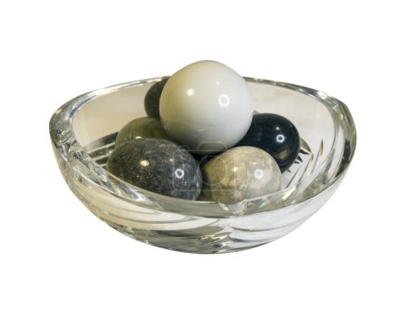 jarrón de cristal con bolas de granito aisladas sobre fondo blanco
