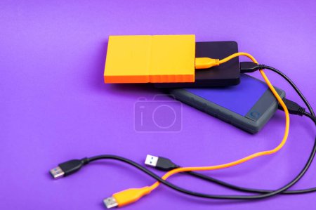 Foto de Unidades de disco duro portátiles externas multicolores aisladas sobre fondo violeta - Imagen libre de derechos