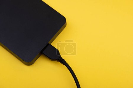 Foto de Unidades de disco duro portátiles externas negras aisladas sobre fondo amarillo - Imagen libre de derechos