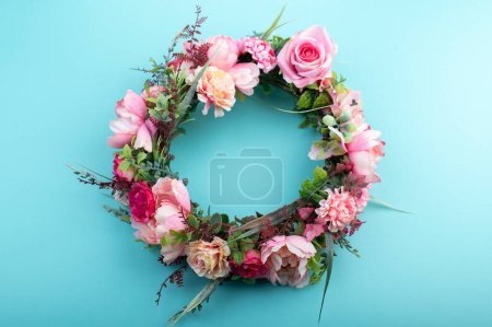 Colorful artificial flowers wreath isolated on light aqua green background