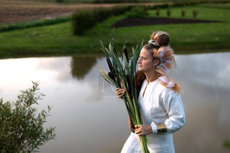 Photo for Young woman with a bulrush grass reed on the background of lake water - Royalty Free Image
