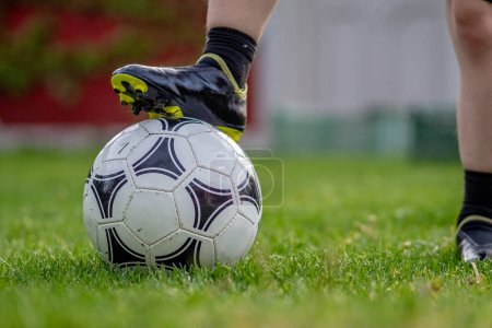 Junge steht während Fußballstunde auf einem Ball auf dem Fußballplatz im Garten