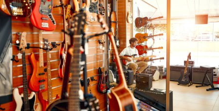Im Hintergrund steht ein bärtiger Lockenkopf mit vielen E-Gitarren in einem Musikinstrumentenladen und versucht, es zu spielen. Hobbys und Erholung. Eine Gitarre im Laden kaufen.