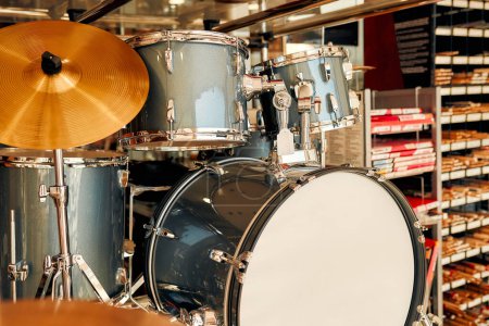 Foto de Buying a drum kit from a musical instrument store. In the background are shelves with drumsticks. Hobbies and recreation. - Imagen libre de derechos