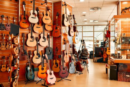 Foto de Un gran surtido de diferentes guitarras colgando en las paredes de una tienda de instrumentos musicales. Aficiones y recreación. - Imagen libre de derechos