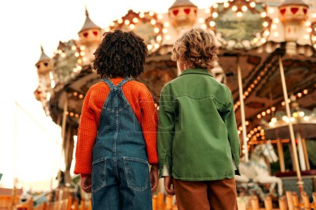 Téléchargez les photos : Une fille afro-américaine et un garçon caucasien avec une coiffure bouclée s'amusent dans un parc d'attractions et de loisirs. - en image libre de droit