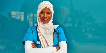 Téléchargez les photos : Une jeune musulmane, médecin en uniforme avec un stéthoscope, se tient dans la rue à l'extérieur de l'hôpital. Médecine et soins de santé. - en image libre de droit