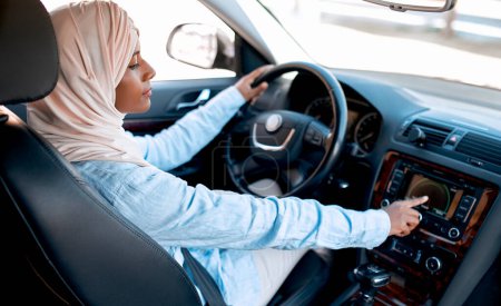 Foto de Joven musulmana en hijab sentada al volante de un coche. Comprar y alquilar un coche. Viajes y recreación. - Imagen libre de derechos