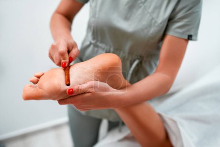 Photo for Woman having a relaxing massage with foot massage stick in the spa beauty salon. Client receiving acupressure treatment with wooden points massager stick. Natural medicine, reflexology, acupressure - Royalty Free Image