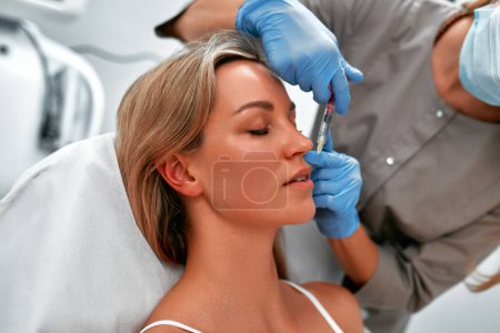 Photo for Medical cosmetology treatments botox injection. Beautician is contouring the woman's face with hyaluronic acid filler. Hyaluronic acid filler is injected by needle or cannula. Face contouring concept. - Royalty Free Image