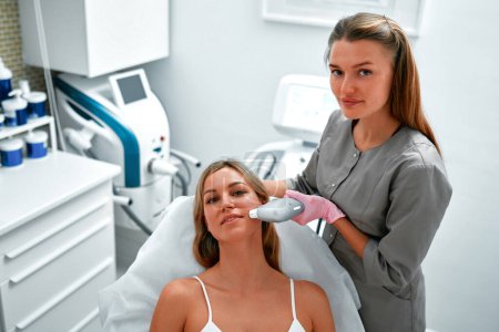 Photo for Relaxed young female client getting SMAS ultrasound face lifting massage with professional equipment in beauty center. Non-surgical facelift. Skin treatment with a laser device. - Royalty Free Image