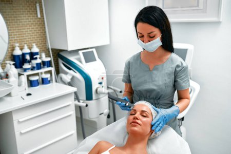 Photo for Skin care. Close-up of beautiful woman receiving ultrasound cavitation facial peeling. Ultrasonic skin cleansing procedure. Beauty treatment. Cosmetology. Beauty Spa Salon. - Royalty Free Image