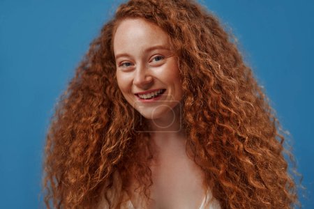 Photo for Young pretty redhead plus size or plump woman celebrating her natural body. Positive beautiful female model in white underwear against blue background. Body positive, skin care and cosmetology. - Royalty Free Image