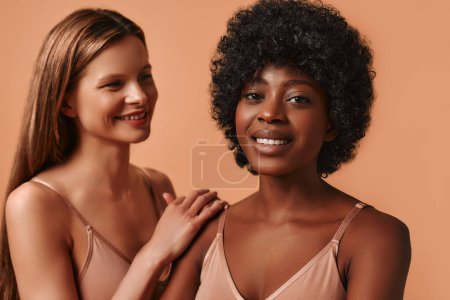 Photo for Close up portrait of a Caucasian and African-American woman with perfect clear radiant skin isolated on a beige background. Cosmetology and spa treatments. Skin care concept. - Royalty Free Image