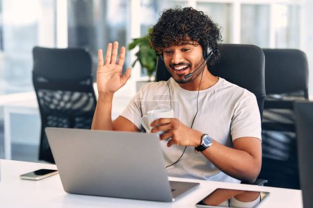 Photo for Technical support operator working with headset in office. Smiling handsome man working as call centre operator, speaking to customer. Happy businessman working remotely while doing video conference. - Royalty Free Image