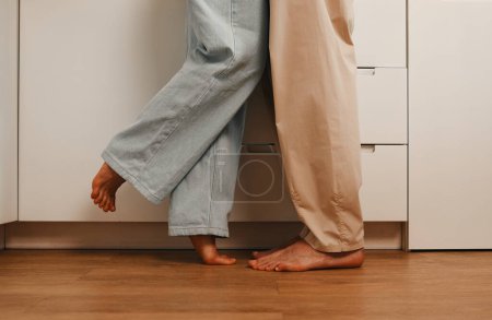 Foto de Foto recortada de una pareja de jóvenes casados enamorados tomados de la mano y abrazándose mientras están de pie en la cocina por la mañana, preparando el desayuno.. - Imagen libre de derechos