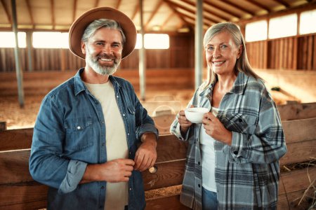 Photo for Mature beautiful couple of farmers drink coffee while relaxing after work in the barn on the farm. Farming and agriculture concept. - Royalty Free Image