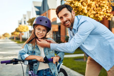 Téléchargez les photos : Un père heureux a appris à sa petite fille à faire du vélo. Un enfant apprend à faire du vélo. Activités familiales en été. - en image libre de droit