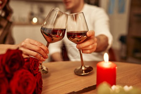 Foto de Feliz día de San Valentín. Una joven pareja enamorada de las copas de vino a la luz de las velas sentada en la cocina a la mesa, pasando románticamente la noche juntos. - Imagen libre de derechos