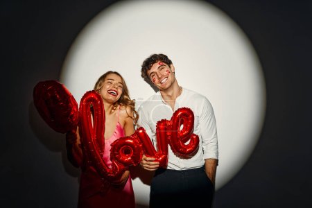 Photo for Happy Valentine's Day. Couple in love holding a balloon with the inscription love on a white background under the light of a spotlight. - Royalty Free Image