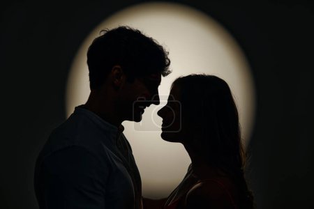 Foto de Feliz día de San Valentín. Siluetas de una pareja amorosa de pie cara a cara a la luz de un foco. - Imagen libre de derechos