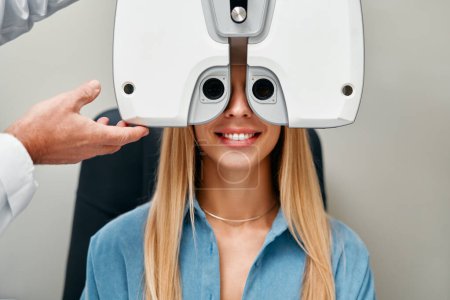 Téléchargez les photos : Une femme effectue un test oculaire avec un optométriste dans un magasin d'optique, Un optométriste vérifie la vision d'une femme dans une clinique. Ophtalmologie et correction de la vue. - en image libre de droit