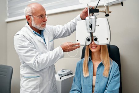 Foto de Una mujer realiza una prueba ocular con un optometrista en una tienda óptica, un optometrista comprueba la visión de una mujer en una clínica. Oftalmología y corrección de la visión. - Imagen libre de derechos