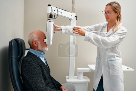Téléchargez les photos : Examen oculaire d'un homme mature avec ophtalmologie diagnostique dans une clinique optique. Examen ophtalmologique professionnel de la vision du patient. Phoropter machine, bilan de santé oculaire. - en image libre de droit