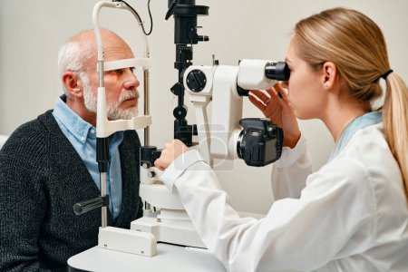 Téléchargez les photos : Examen de la vue des hommes matures consulter un médecin pour la vue chez l'optométriste ou l'ophtalmologiste. Visage de la vision de test client senior avec aide opticien ou test de santé visuelle de l'iris ou de la rétine. - en image libre de droit