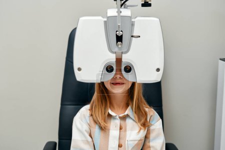 Photo for Cute girl child doing eye test checking examination with optometrist in optical shop. Optometrist doing sight testing for child patient in clinic. Ophthalmology and eye correction. - Royalty Free Image
