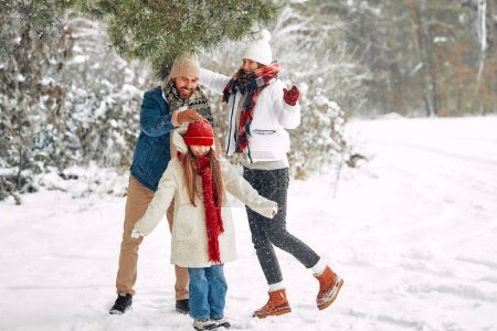 Téléchargez les photos : Joyeux Noël et bonne année. Famille heureuse avec un enfant et jouer et s'amuser dans le contexte de la forêt par temps neigeux. - en image libre de droit