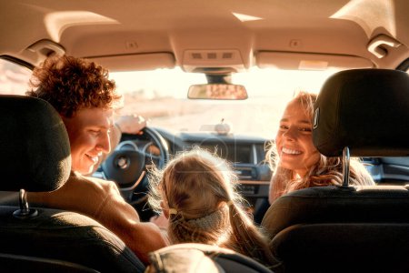Téléchargez les photos : Toute la famille conduit pour le week-end. Maman et papa avec leur fille sont assis dans la voiture. Loisirs, voyages, tourisme. - en image libre de droit