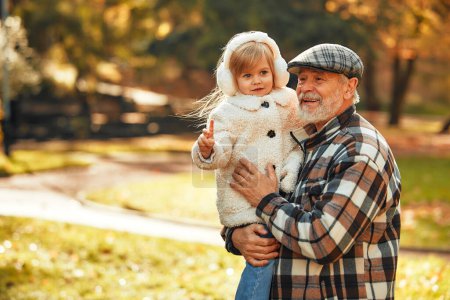 Foto de Abuelo caminando y jugando con su linda nieta en el parque en otoño. - Imagen libre de derechos
