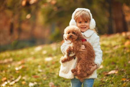 Foto de Lindo niño niña paseando con su amigo perro en el parque en otoño. - Imagen libre de derechos