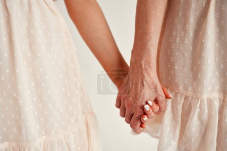Photo for Mother's day and women's day concept. Cropped photo of mother and daughter holding hands isolated on white background. - Royalty Free Image