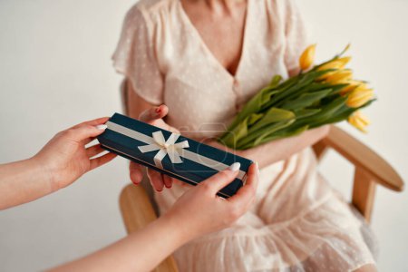 Téléchargez les photos : Joyeuse fête des mères et fête des femmes. Charmante fille offrant à sa mère un cadeau et un bouquet de tulipes isolées sur fond blanc. L'amour et les soins de mère. - en image libre de droit